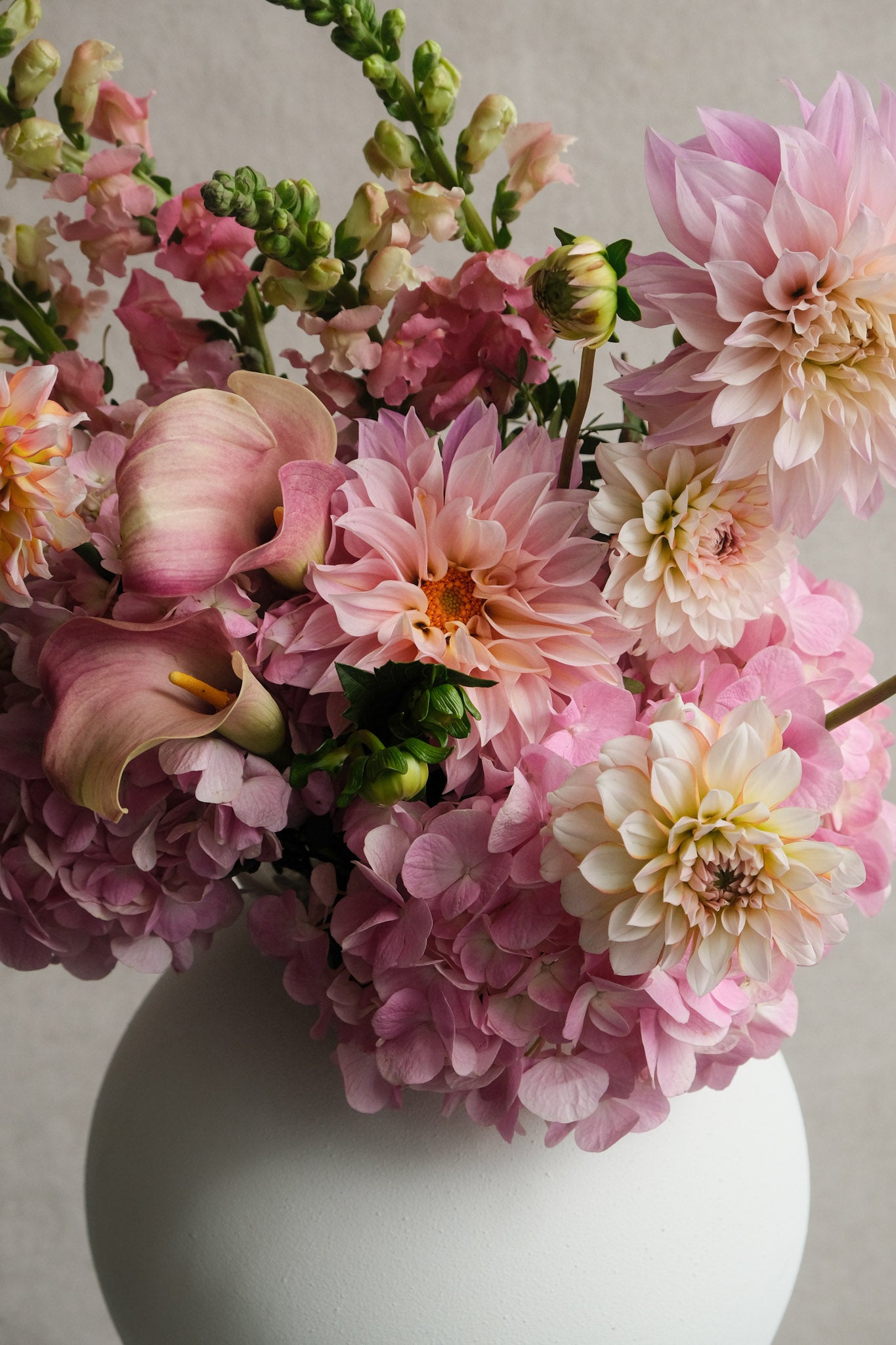 Bouquet of pink and white flowers in a white vase against a neutral background