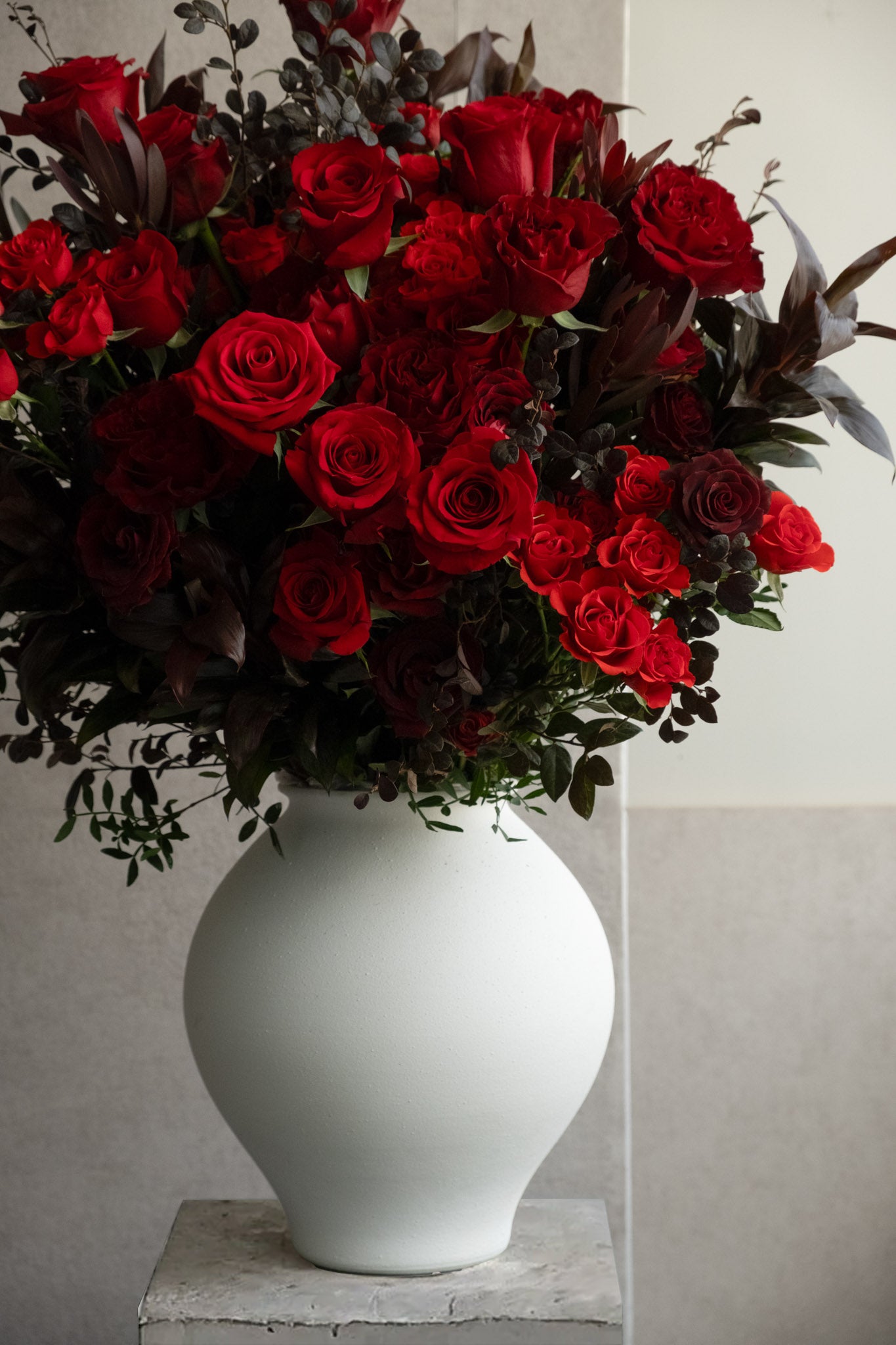 Bouquet of red roses in a white vase against a light background