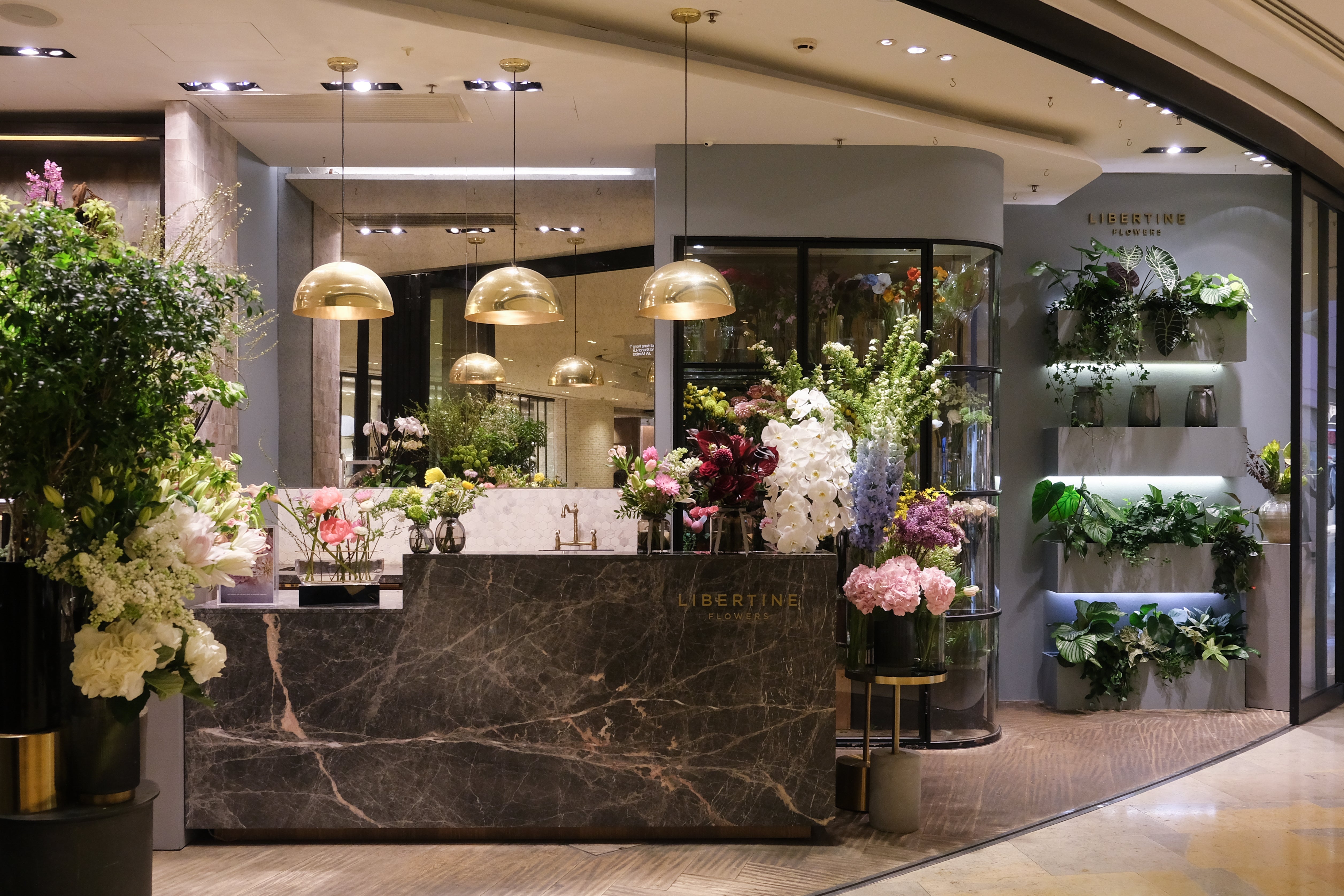 Floral display in a modern interior setting with marble counter and decorative lighting.