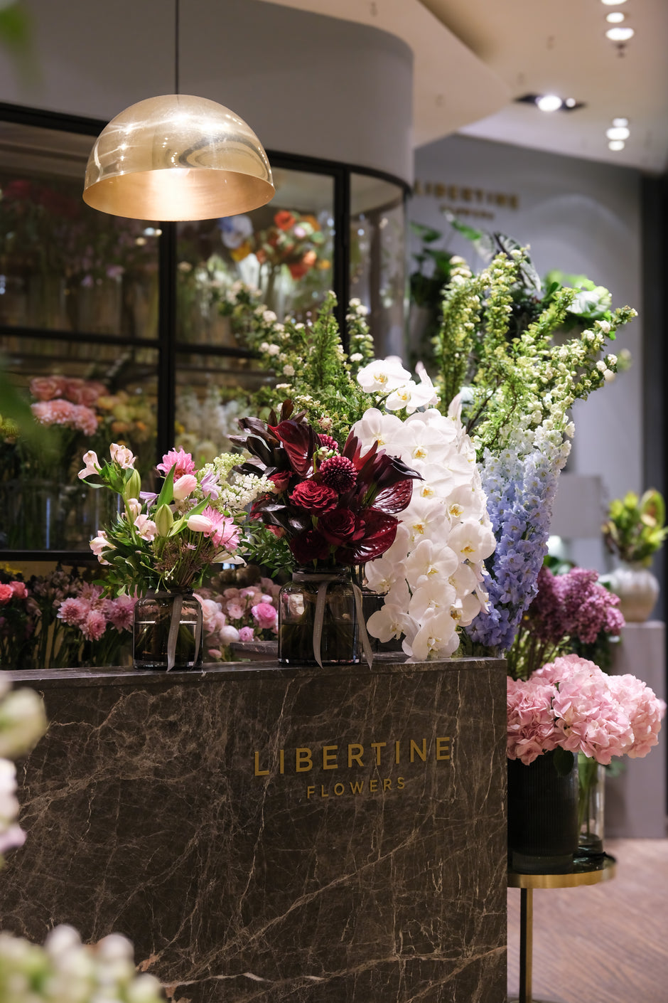 Floral arrangements on a counter with 'Libertine Flowers' branding in a store setting.