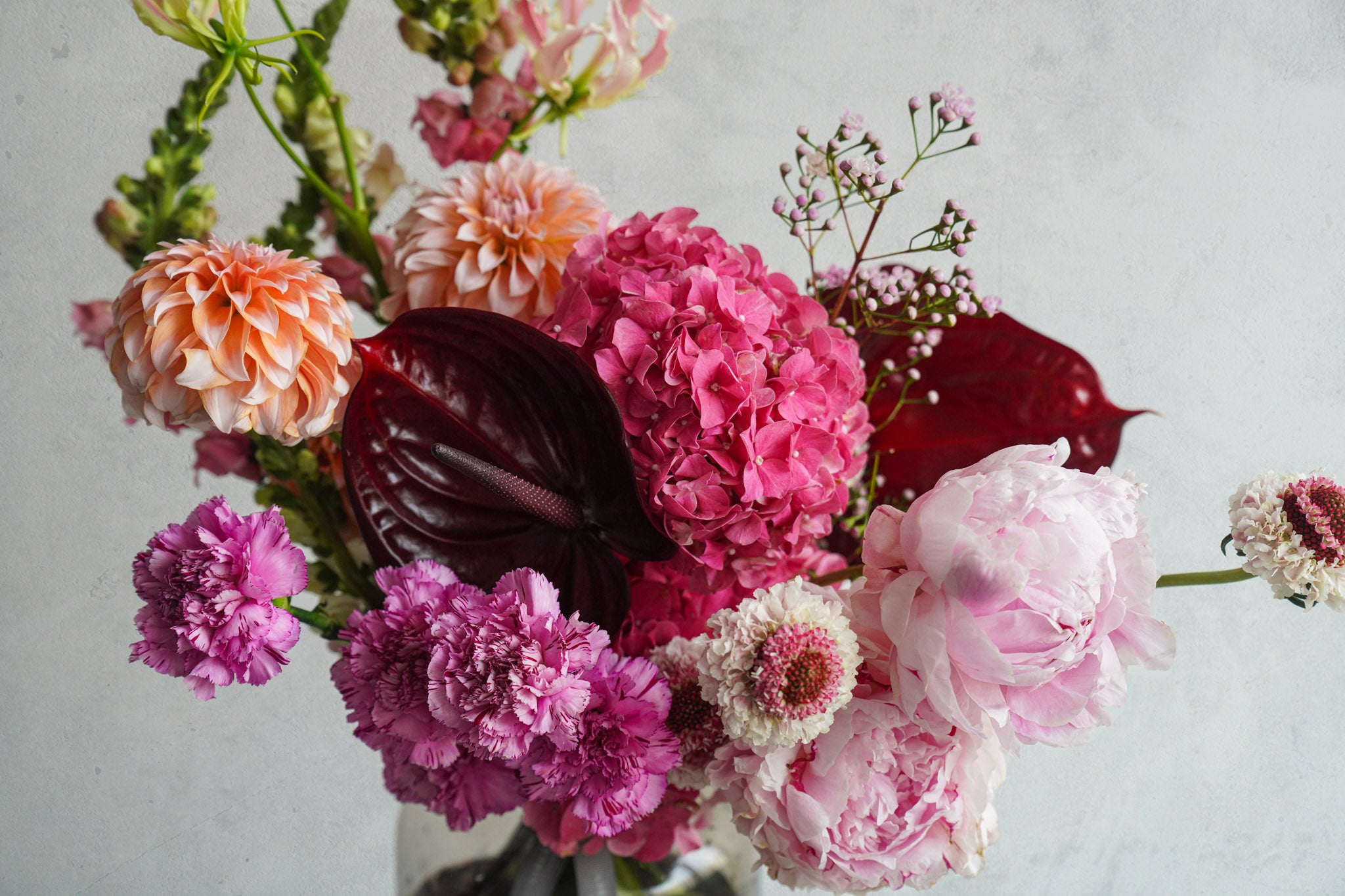 Colorful flower arrangement with pink, red, and white flowers on a light gray background